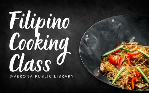 a metal wok style skillet sits on a table with stir-fried vegetables, pork, and rice noodles with a sauce