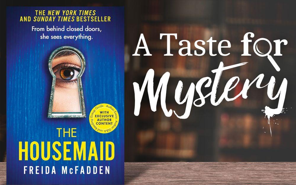 "The Housemaid" book cover on a wood table in a dark library